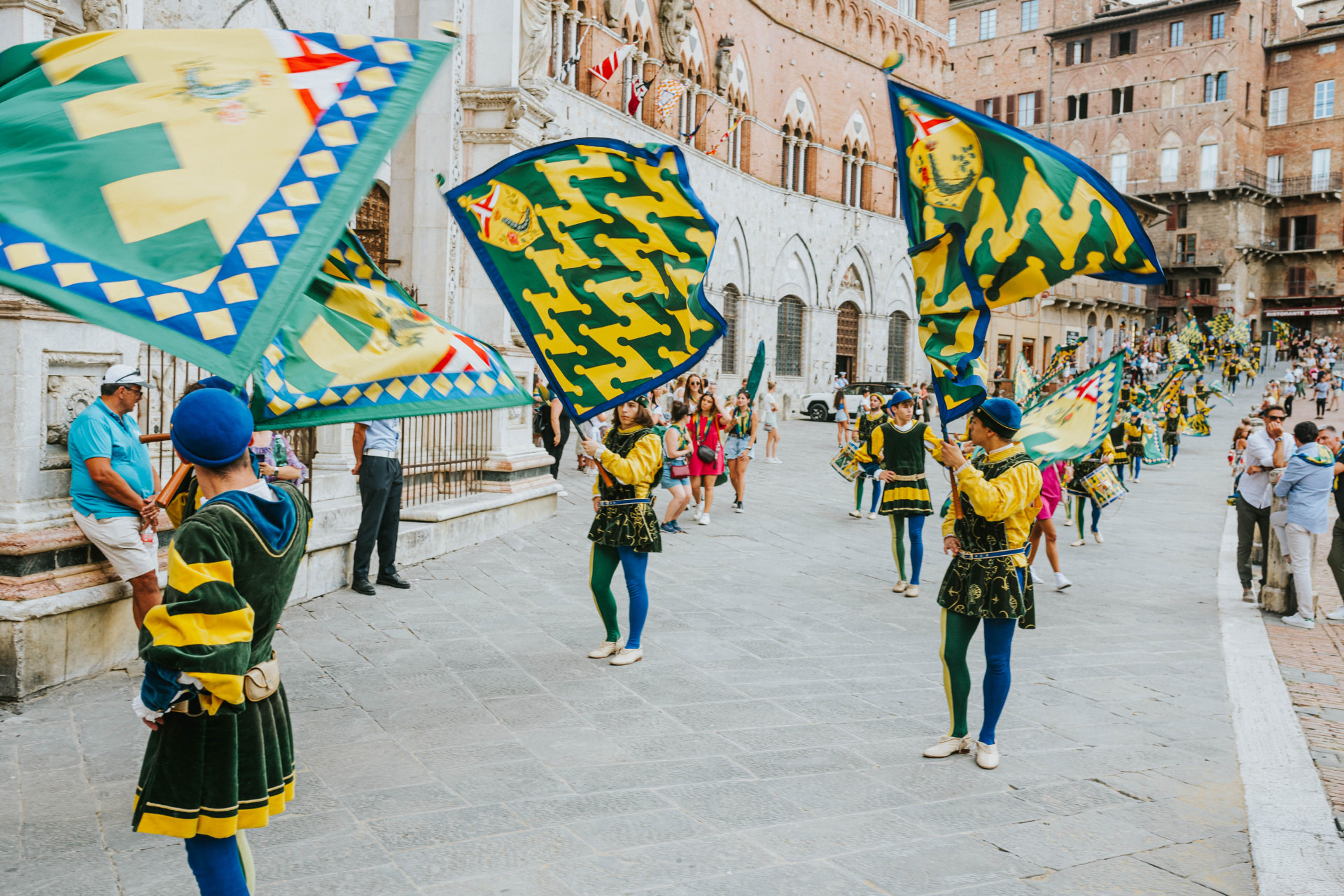 Costumed flag-wavers and drummers of a Sienese contrada processing across Piazza del Campo